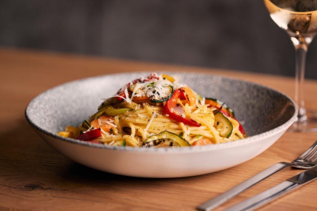 Pasta mit buntem Gemüse und Parmesan in einer eleganten Schüssel